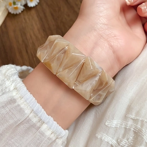 Macro detail of geometric acrylic bangle with marble texture on a woman wrist
