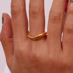 Close-up of a minimalist 18K gold plated stainless steel wavy ring worn on a finger