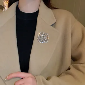 Elegant silver hollow rose flower brooch with inlaid rhinestones on a beige wool coat