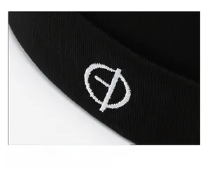 Detail of black knit beanie featuring white embroidered symbol and fine ribbed texture