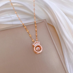 Macro shot of rose gold crown necklace with dancing diamond stone on beige tray