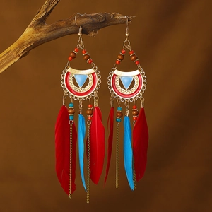 Detail of bohemian red and blue feather earrings hanging on a rustic wooden branch