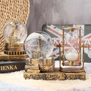 Detailed retro Eiffel Tower crystal ball with bronze hourglass on a vintage book base