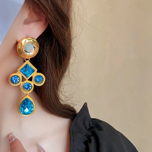 Close-up of vintage gold earrings with blue gemstones worn by a model in soft lighting