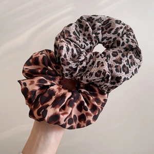 Detail showing two soft leopard print satin scrunchies with elegant silk texture
