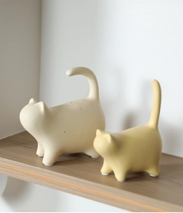 Detail of minimalist ceramic cat statues with matte texture and anti-slip pads on wood