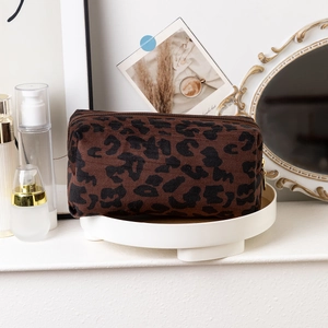 Detailed view of leopard print cosmetic bag with knitted texture on a vanity display