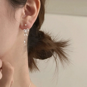 Elegant silver bow ribbon earrings with tassel design worn by a female model
