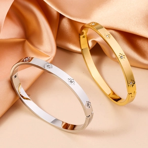 Detailed view of gold and silver stainless steel bangles with floral star engravings