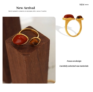 Detail of gold-plated titanium steel ring with red stone and tiger eye in geometric design