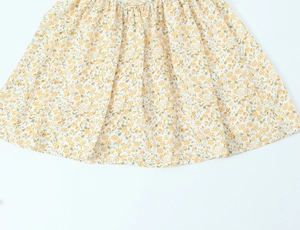 Détail de l'imprimé floral jaune et de la texture froncée sur une robe d'été blanche