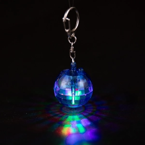 Detail showing the glowing blue LED disco ball keychain with reflective facet texture