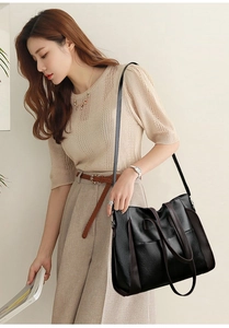 Elegant woman wearing a black minimalist large tote bag with soft leather texture