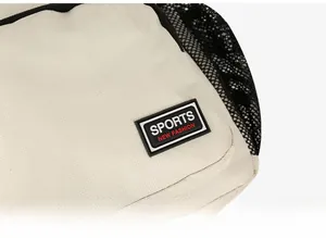 Detail of canvas crossbody bag showing a black sports logo patch and mesh side pocket