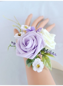 Detail of lavender and white silk rose wrist corsage with green leaves and ribbon