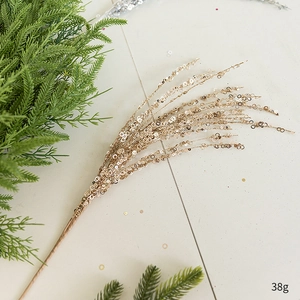 Detail view of golden sequin Christmas tree spray branch with sparkling glitter texture