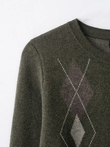 Détail macro d'un pull en maille vert foncé avec motifs classiques de losanges et texture