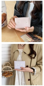 Close-up of women's mini wallet with bow and pearl detail in pink and lilac colors