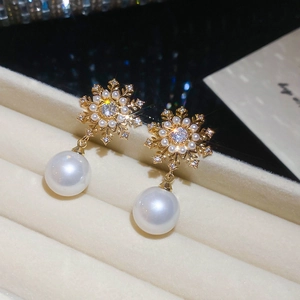 Macro shot of snowflake pearl earrings with cubic zirconia inlay on beige velvet