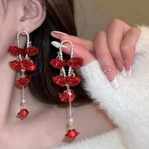 Dettaglio degli orecchini a rosa rossa con perle bianche e strass brillanti incastonati