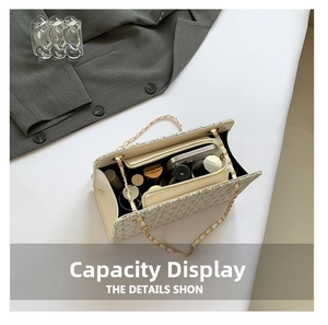 Internal view of tweed chain bag showing capacity for phone and cosmetics with zip pocket