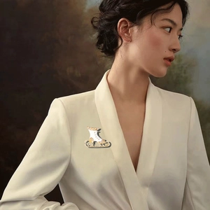 Detail view of a white enamel ice skate brooch with crystals on a white blazer lapel