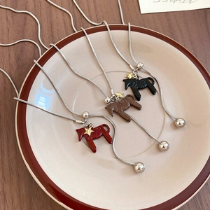 Detail of horse pendants in red, brown and black with gold star on ceramic tray