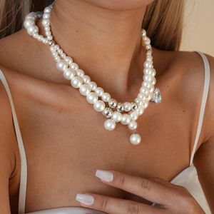 Detail of double-layer pearl necklace with a teardrop gemstone pendant on a model