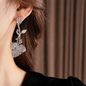 Nahaufnahme eines silbernen Blumen-Ohrrings mit schimmernden Zirkonia-Kristallen am Model