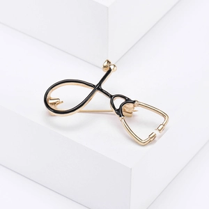 Minimalist gold stethoscope brooch pin for doctors and nurses on white geometric stand