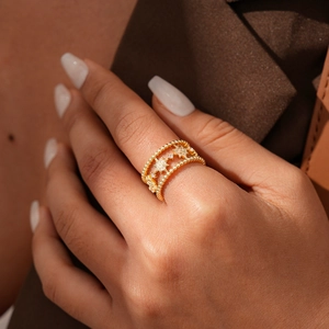 Dettaglio anello a stella vintage in oro con zirconi e bordi milgrain sulla modella