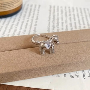 Macro detail of horse-shaped open ring featuring a sparkling heart zircon on a display stand