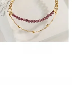Detail of layered gold steel chain featuring purple beads and tiny gold spheres