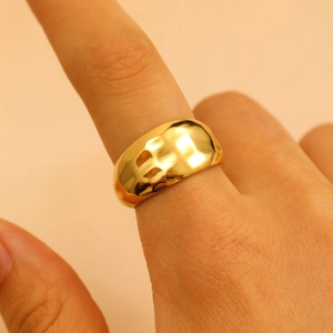 Detail shot of a golden irregular hammered texture stainless steel ring worn on finger