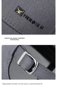 Detail of adjustable metal buckle and embroidered HEROISM logo on grey baseball cap