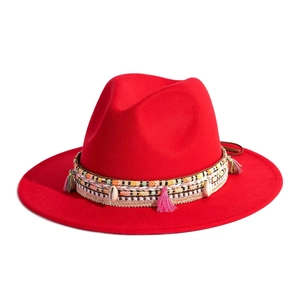 Detail of red fedora hat featuring a woven band with colorful tassels and white shells