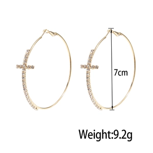Detail shot of 7cm gold hoop earrings with crystal-encrusted cross charms and weight info