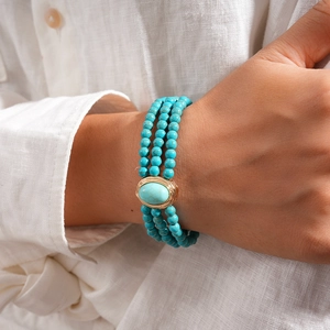 Detail of bohemian turquoise multi-strand beaded necklace on white linen shirt