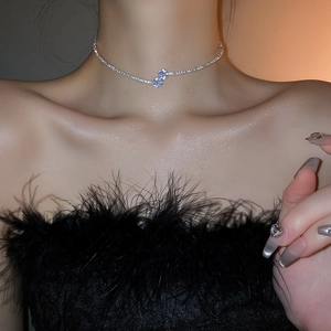 Detail view of a silver choker necklace with a sparkling clover zircon pendant on a neck