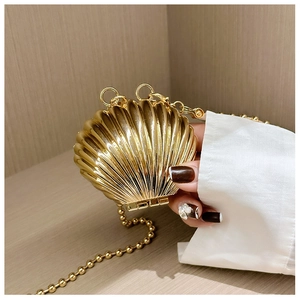 Detail of mini gold shell purse with radial texture and golden bead chain strap