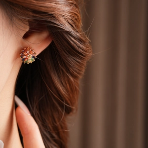 Detail of flower stud earrings with colorful crystals and pearl on model's ear