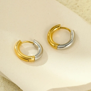 Macro view of C-shaped stainless steel earrings featuring two-tone gold and silver finish