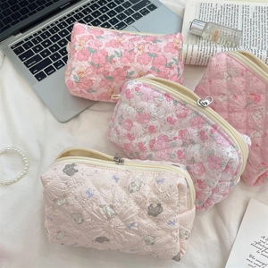 Quilted floral makeup bags in pink and cream patterns with metal zipper details
