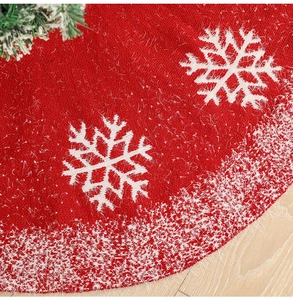 Close-up of red knitted Christmas tree skirt with white snowflakes and faux fur trim