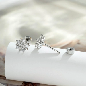 Star-shaped silver ear studs with sparkling cubic zirconia on a white pedestal