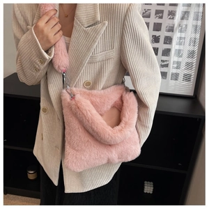 Dettaglio della borsa a tracolla in peluche rosa con ganci metallici su una modella