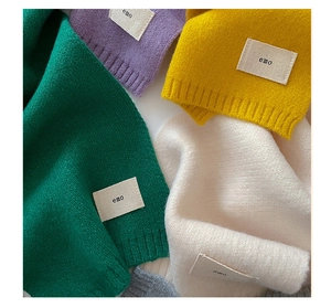 Close-up of knit scarves in green, purple, yellow, and grey with emo labels