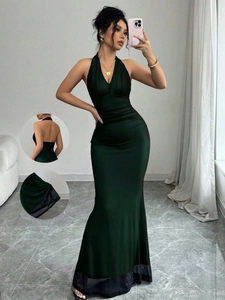 Detail of dark green backless fishtail dress with sheer black mesh hem and halter neck