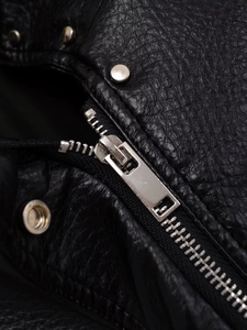 Détail de la fermeture éclair en métal argenté et des rivets sur une veste en similicuir noir