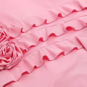Detail of pink dress featuring layered ruffles and handcrafted 3D rose fabric flowers